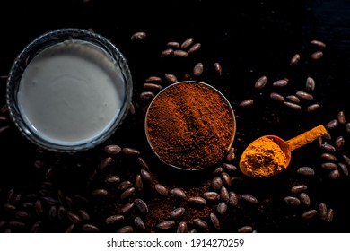 Coffee Face Mask For Treating Oily Skin And For Skin Whitening On A Black Colored Shiny Surface Consisting Of Some Coffee Beans Powder, Turmeric Powder, And Yogurt.