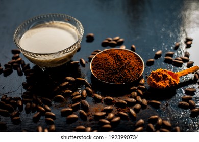 Coffee Face Mask For Treating Oily Skin And For Skin Whitening On A Black Colored Shiny Surface Consisting Of Some Coffee Beans Powder, Turmeric Powder, And Yogurt.