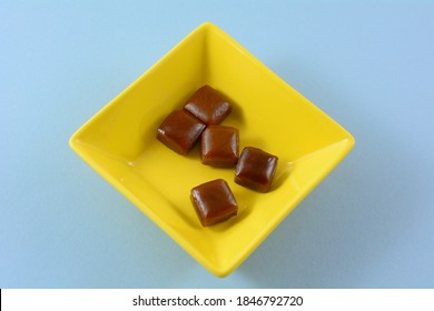 Coffee Flavored Hard Candy In Yellow Candy Dish On Blue Background