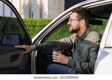 Coffee to go. Handsome man with paper cup of drink in car outdoors - Powered by Shutterstock