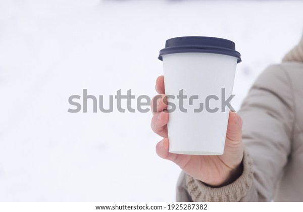 Coffee to go. A paper cup in a hand with an empty\
space for the logo.
