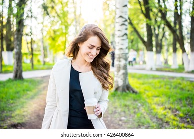 Coffee To Go. Young Woman Portrait. Happy Young Stylish Business Woman Walking In The City Park Along And Drinking Coffee.