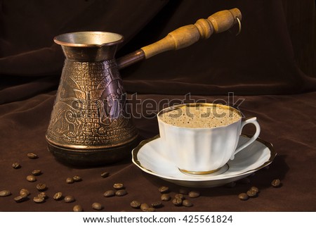 Coffee grinder, cup on the table. Brown background, still-life, tableware. Drinking coffe, book. Cezve, Ibrik brewing coffee oriental ornaments form ancient oriental emblem, dried fruits. 