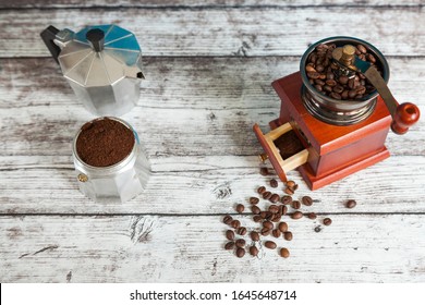 Coffee Grinder With Coffee Grains And Italian Coffee Maker With Ground Coffee On Wooden Table From Above. Top View