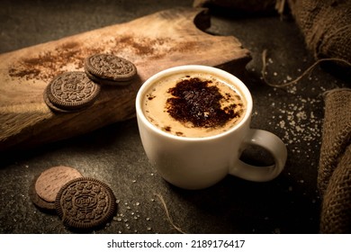 Coffee, hot coffee a beverage that is served hot in white coffee cup photo is composited with Oreo biscuits piece of rustic wooden surface. added coco powder on top of coffee. copy space in it.