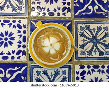 Coffee Latte With Beautiful Flower Latte Art. Yellow Cup On Blue Table.