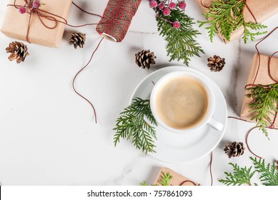 Coffee Latte Mug With Christmas Gift Or Present Box Wrapped In Kraft Paper, Decorated With Christmas Tree Branches, Pine Cones, Red Berries, On White Marble Table, Copy Space Top View