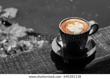 Coffee latte on the wood table by the river, pond or lake