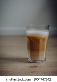 Coffee latte in a tall glass with cream poured