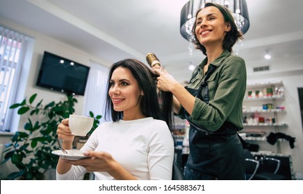 Coffee And Leisure. Low Angle Shot Of A Young Girl With Perfect Makeup Drinking Coffee While Getting Her Hair Done In A Hair Salon.