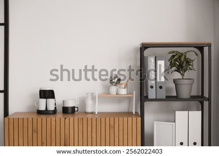 Coffee machine with cups on commode in office