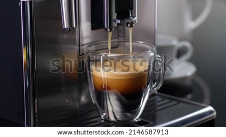 Coffee machine filling a cup with expresso. Transparent mug in automated coffeemaker machine. Beverage drink for breakfast