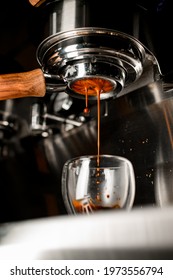 Coffee machine pouring coffee in double wall glass from bottomless naked portafilter. Professional equipment at home or cafe.