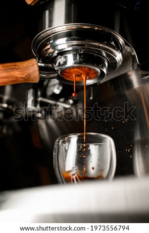 Coffee machine pouring coffee in double wall glass from bottomless naked portafilter. Professional equipment at home or cafe.