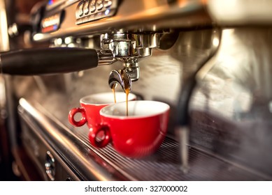 coffee machine preparing fresh coffee and pouring into red cups at restaurant, bar or pub.