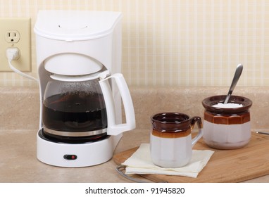 Coffee Maker, Cup Of Coffee And Sugar Bowl On A Kitchen Counter