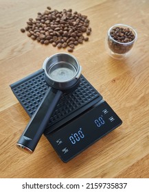 Coffee maker horn lies on coffee scales, on the background of wooden countertops, coffee beans and cups with coffee beans
