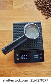 Coffee maker horn lies on coffee scales, on the background of wooden countertops, coffee beans and cups with coffee beans