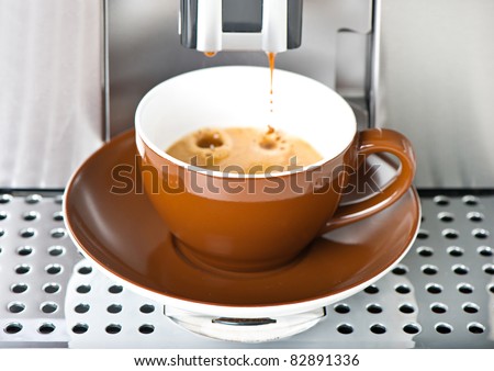 Coffee maker pouring fresh coffee in a cup. Selective focus