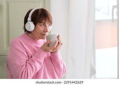 Coffee and melodies: cheerful senior lady by the window - life's simple pleasures - Shutterstock ID 2291442629