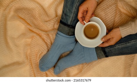 Coffee with milk in the comfort of a warm blanket.Coffee with milk in the comfort of a warm blanket. Woman in blue socks and jeans with a cup of coffee in her hands on a knitted shawl