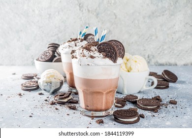 Coffee mocha milkshake with cookies and cream. Ice cream and chocolate cookies sweet latte cocktail. On gray concrete table, with spoon and cup of vanilla ice cream. Copy space