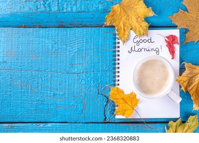 tazón de café con ramo de flores y hojas de otoño, notas buenas mañanas sobre la mesa azul turquesa de madera, desde arriba, desayuno acogedor y hermoso otoño, tarjeta de época, vista superior, piso