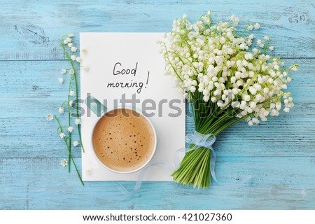 Coffee mug with bouquet of flowers lily of the valley and notes good morning on turquoise rustic table from above, beautiful breakfast, vintage card, top view, flat lay