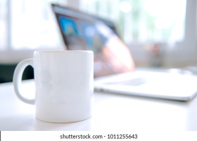 Coffee mug and laptop in office table interior
