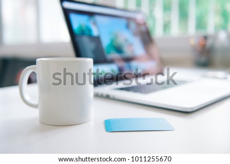 coffee mug and laptop in office table interior with business card
