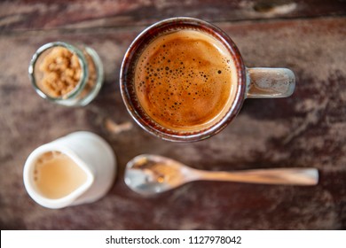 Coffee Mug With Milk Creamer Brown Sugar Jar And Spoon On Wooden Table Top View In Morning