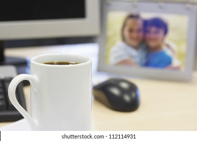 Coffee Mug On Table With Family Photo In Background