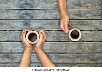 Coffee Mugs Hands Holding On Wood Table, Top View Angle