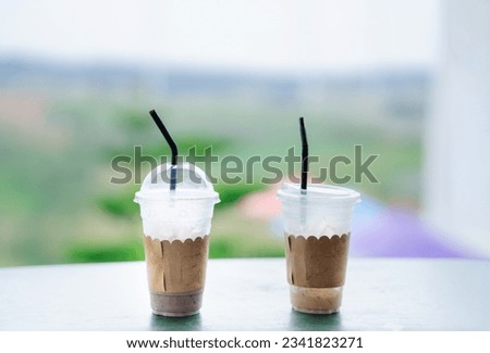 coffee mugs, with straws, plastic, supply is almost over, on wooden table, with beautiful nature view, coffee consumption, in disposable cups, with ice.