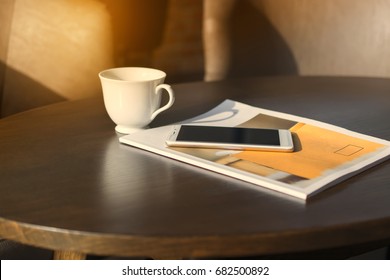 Coffee mugs, telephones and magazines are available on  wooden table. - Powered by Shutterstock