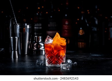 Coffee negroni red cocktail drink with dry gin, vermouth and bitter, espresso, liqueur, orange and ice. Black bar counter background