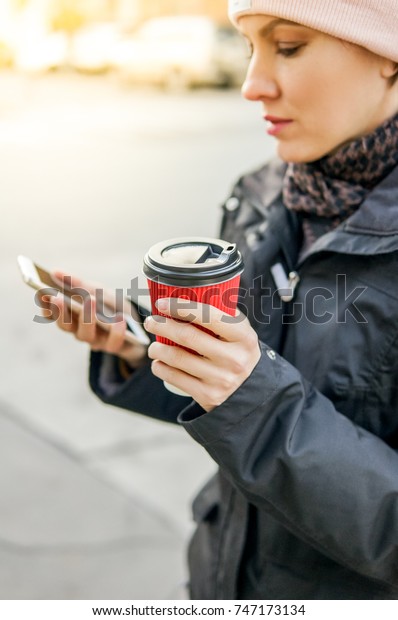 Coffee on the go. Autumn woman holding coffee\
while walking along the\
street