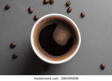 Coffee in a paper cup on the table. Freshly brewed coffee in a disposable paper cup on the table. Grains of coffee near a glass of coffee