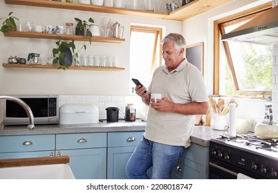 Coffee, Phone And Elderly Man In Kitchen Texting And Reading News Or Social Media In His Home. Happy, Communication And 5g Network With Senior Male Enjoying Fast Internet And Online App Conversation