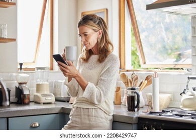 Coffee, phone and senior woman in kitchen browsing social media, text message or online app at home. Relax, tea and reading news or mobile online web surfing with female from Canada on 5g smartphone - Powered by Shutterstock