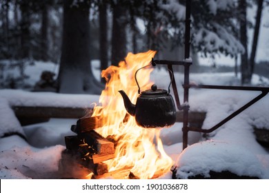 Coffee Pot Hanging Over The Fire Outside In The Winter. Winter Theme. Camping, Hiking Concept.