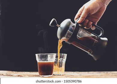 Coffee is poured into a cup from French press coffee maker , On the  old wood table and black background, Natural light, Selective focus, Vintage style. - Powered by Shutterstock