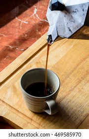 Coffee Is Poured From A Kettle On The Stove Top Down A Cup Of Coffee.