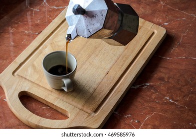 Coffee Is Poured From A Kettle On The Stove Top Down A Cup Of Coffee.