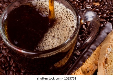 Coffee pours into a glass cup surrounded by coffee beans.
