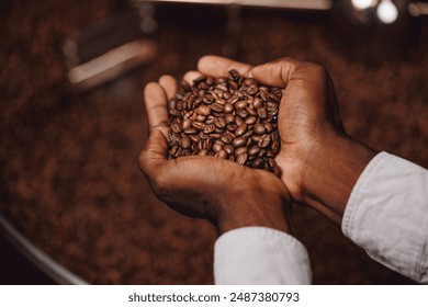 Coffee production industry of Africa. Closeup hands of african american barista hold fresh brown beans on background roasting machine. - Powered by Shutterstock