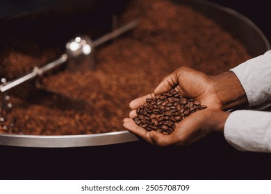 Coffee production industry of Africa. Closeup of african american barista hands holding brown beans on background roasting machine, Top view. - Powered by Shutterstock