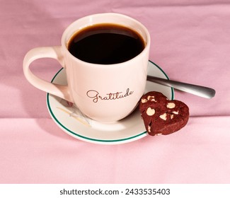 coffee served in a pink cup next to a red chocolate cookie with white heart-shaped chocolate chips - Powered by Shutterstock