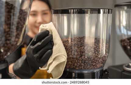 Coffee Shop Cleaning Staff Wiping Coffee Bean Grinder with Cloth in Modern Cafe Setting - Powered by Shutterstock