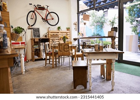 Coffee shop, empty interior and space with table, chairs and furniture or small business, bistro and cafe with unique design and style. Background, creative startup and food store with bike on wall